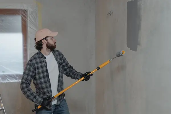 Painter rolling grey paint onto an interior wall in Eugene