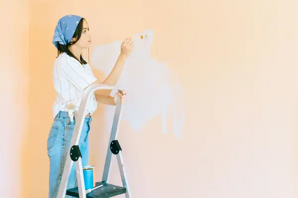 Interior painting in Eugene: painter on a stepladder rolling a wall